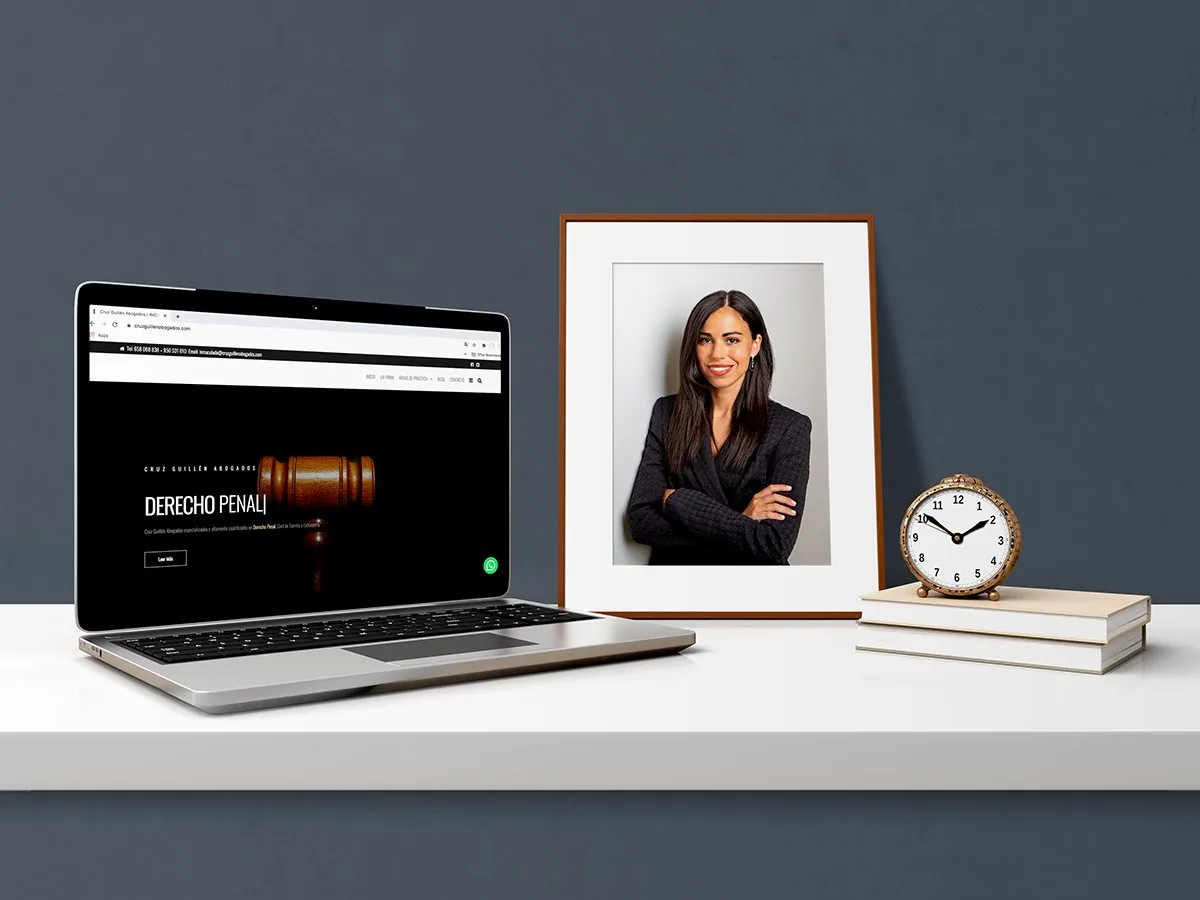 Web de Cruz Guillén Abogados en un portátil junto al retrato de la abogada